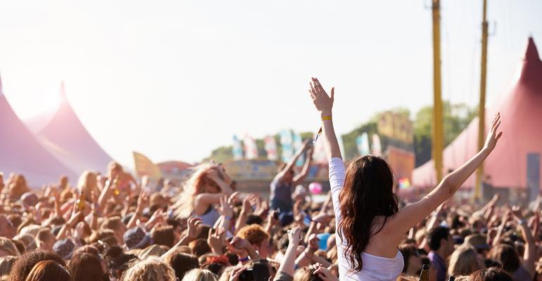 Woman at music festival with arms in air